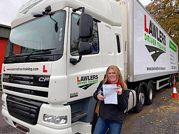 Newly qualified female class 1 artic with trailer category c + e  hgv driver holding pass certificate in front of HGV truck