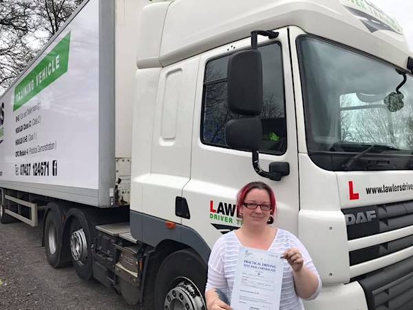 Newly qualified class 1 artic with trailer category c + e  hgv lady driver holding pass certificate in front of HGV truck