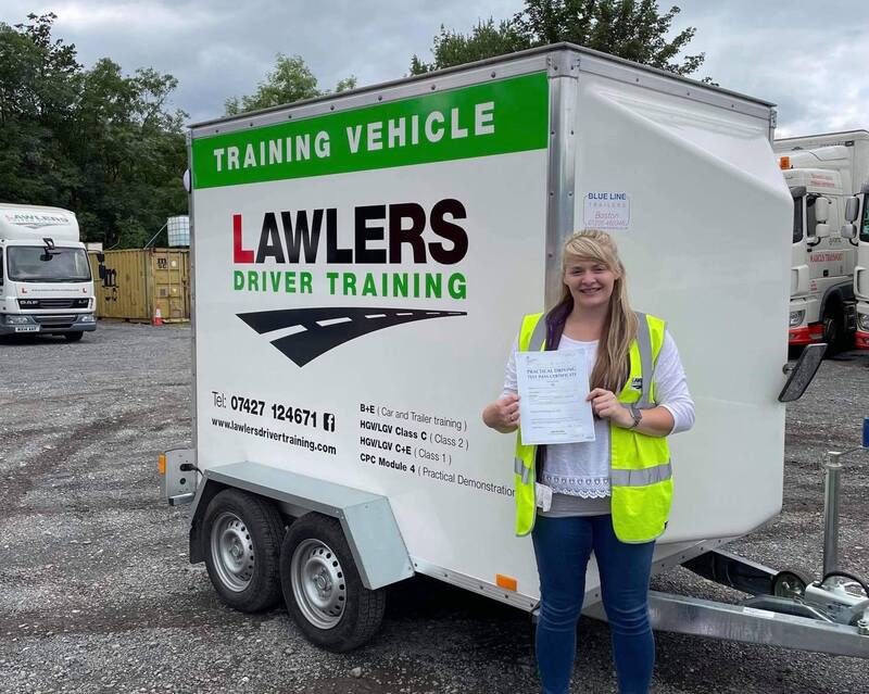 Woman holding pass certificate in front of Car & Trailer tow training trailer in Keighley