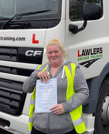 Newly qualified female class 1 artic with trailer category c + e  hgv driver holding pass certificate in front of HGV truck
