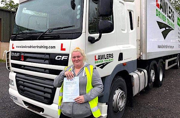 Woman holding pass certificate in front of HGV Class 1 Category C+E Training Vehicle near Bradford