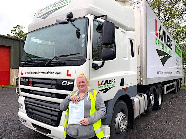 Newly qualified lady class 1 artic with trailer category c + e  hgv driver holding pass certificate in front of HGV truck