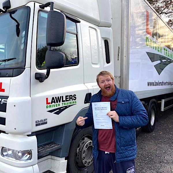 Happy newly qualified class 1 artic with trailer category c + e  hgv driver holding pass certificate in front of HGV truck