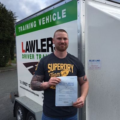Newly qualified trailer towing driver holding b+e pass certificate in front of  trailer training vehicle