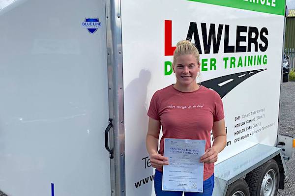 Female holding pass certificate in front of Car & Trailer tow training trailer in Keighley
